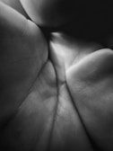 The image features a close-up view of the lines and textures on a palm, with detailed focus on the skin patterns and creases. The black and white tone enhances the intricate details and shadows.