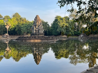 A serene temple in Bali surrounded by lush greenery and calm water reflecting the sky.