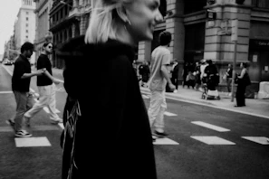 A black and white photo of a crowded city street showing diverse pedestrians in motion.