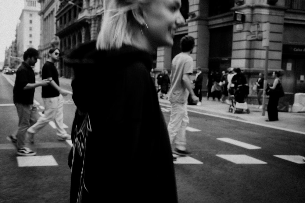 a black and white photo of people crossing the street