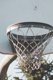 Close-up of a basketball hoop with a net swaying gently outdoors.