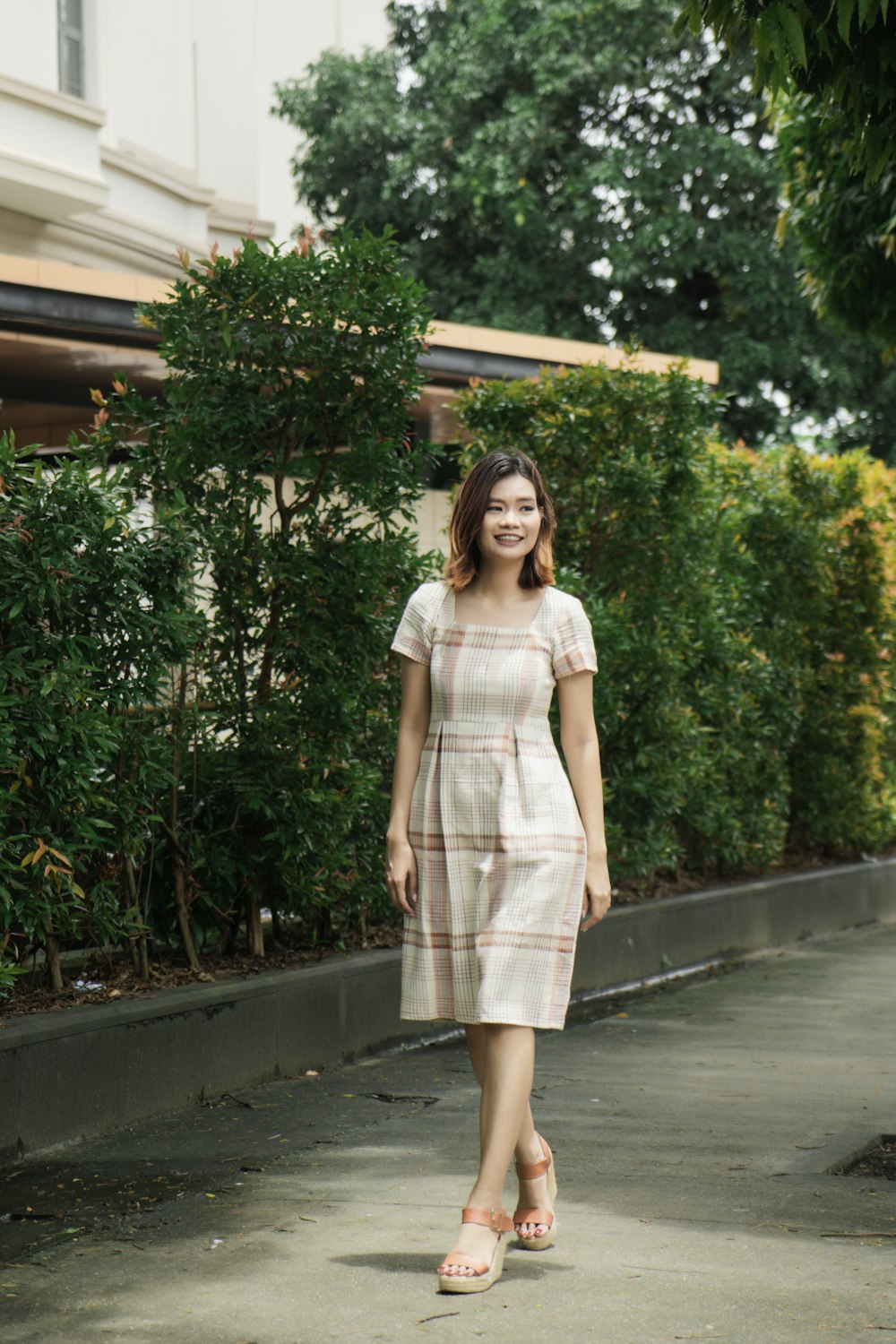 a woman in a dress walking down a sidewalk