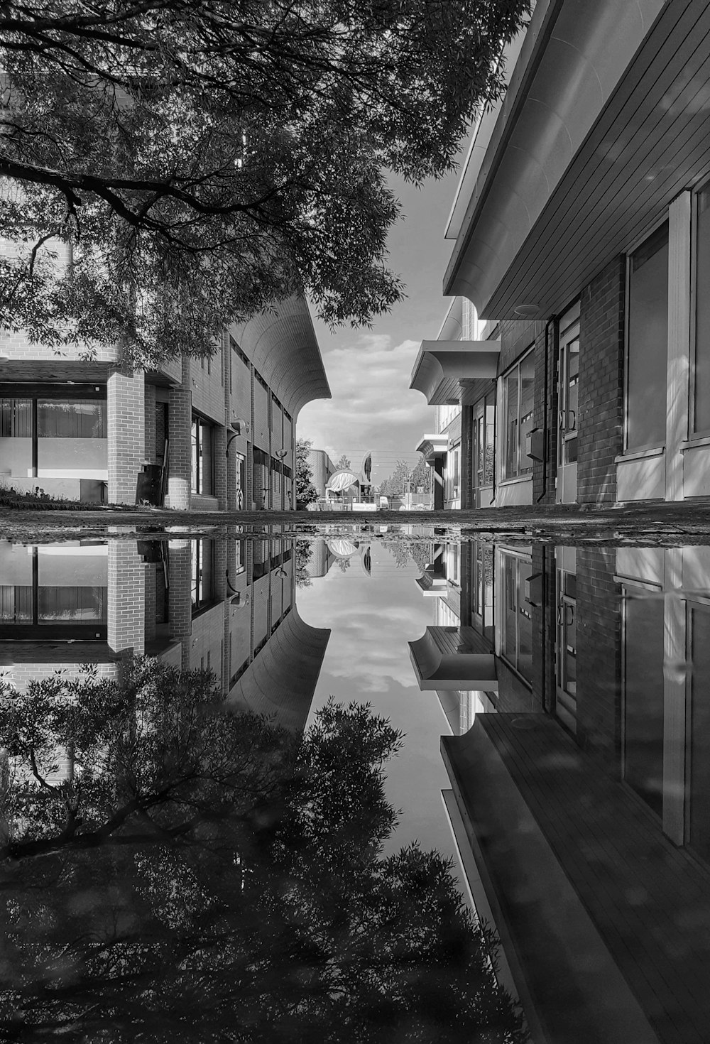 a black and white photo of a building reflecting in a pool