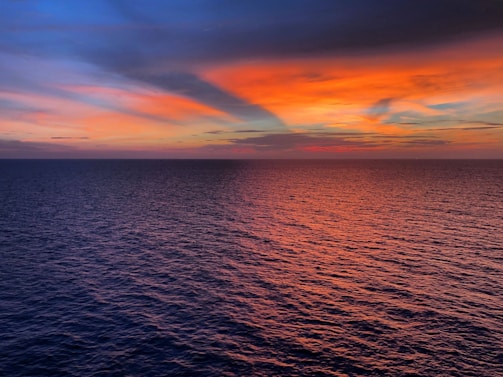 A vibrant custom painting of a sunset over a calm sea, showcasing warm oranges and deep blues.