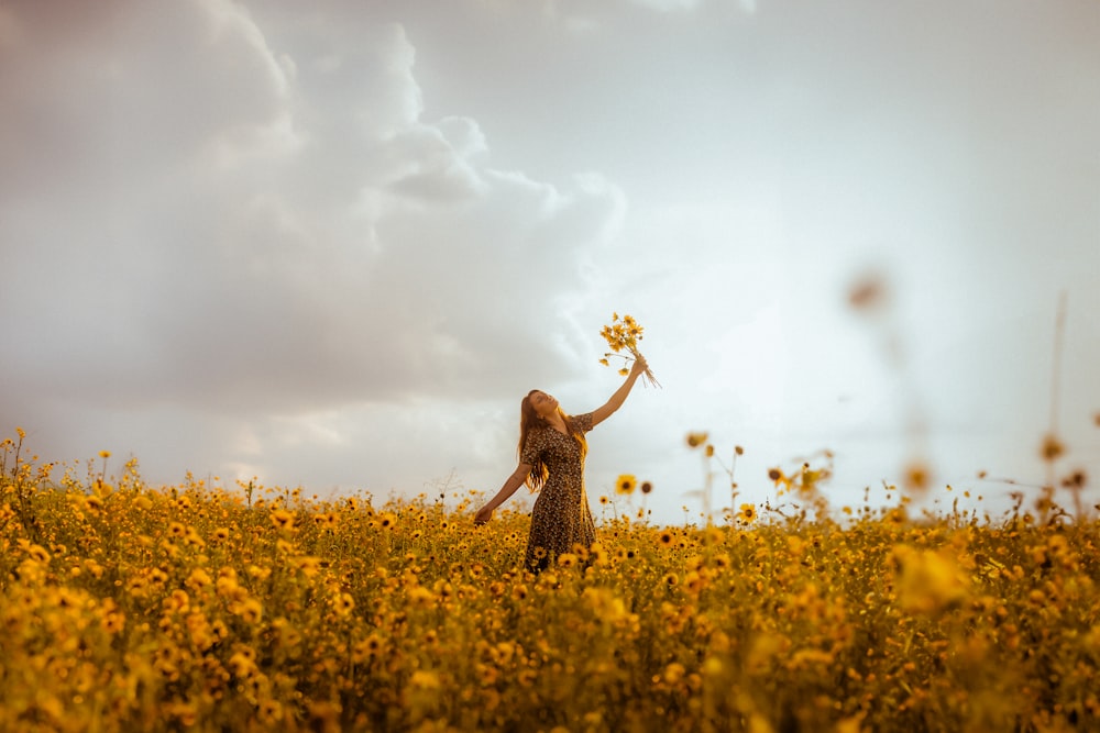 a woman in a field holding a bunch of flowers