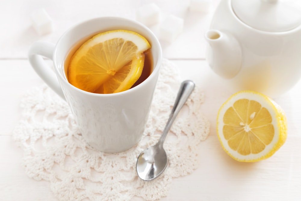 a cup of tea with lemon slices and a spoon