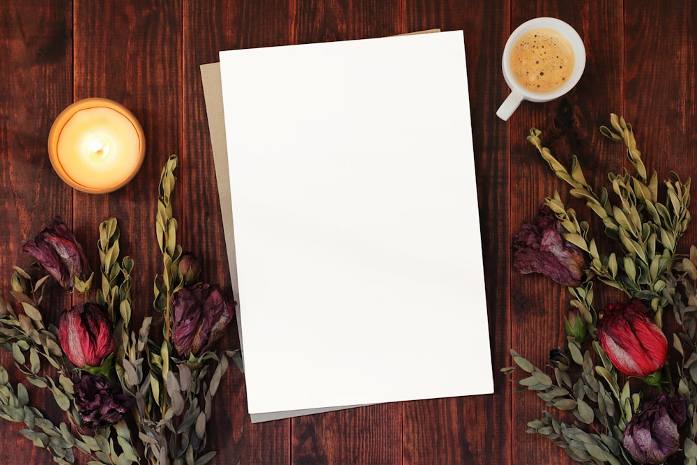 a blank paper next to a cup of coffee and flowers
