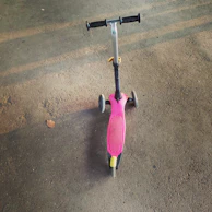 A foldable kick scooter with big PU wheels standing on a sunny park path.