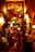 A warmly lit entrance to an Argentine grill, decorated with colorful lights and various objects. The eclectic décor includes hanging lamps, signs, and a red duct. Two people are seen entering the establishment, which is filled with vibrant and inviting lighting.