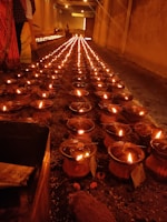 Devotees lighting traditional oil lamps inside a peaceful temple hall.