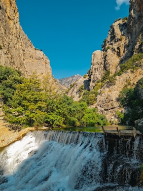 A serene view of Jonha Fall Resort surrounded by dense greenery and a flowing river under a clear sky.