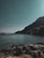A serene coastal landscape with calm waters and distant mountains under a clear sky.