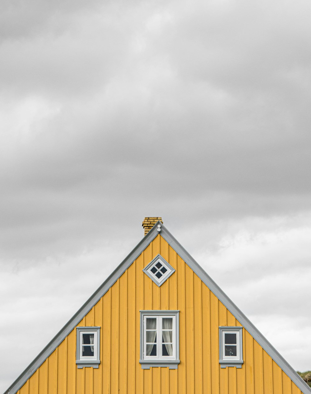 a yellow house with a clock on the top of it