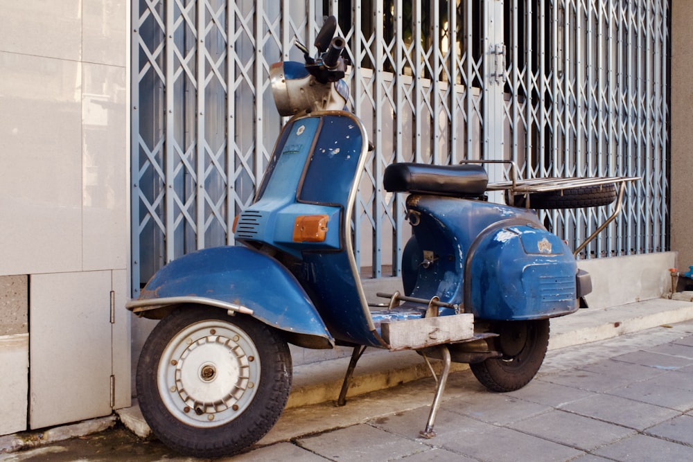 a blue motor scooter parked next to a building