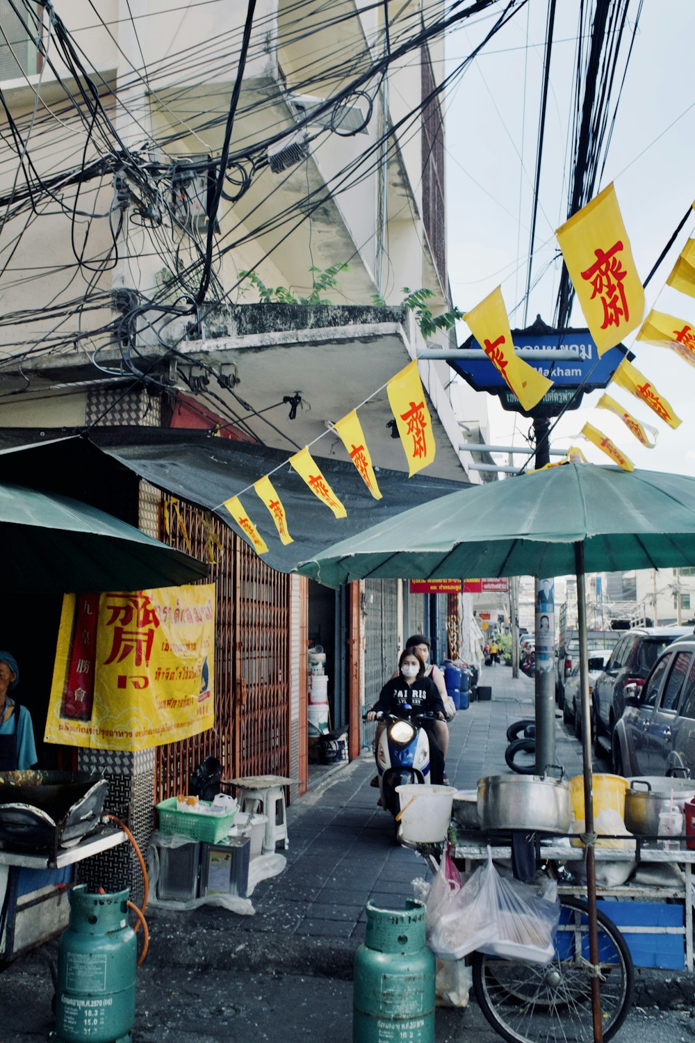 a man riding a motorcycle down a street under a green umbrella