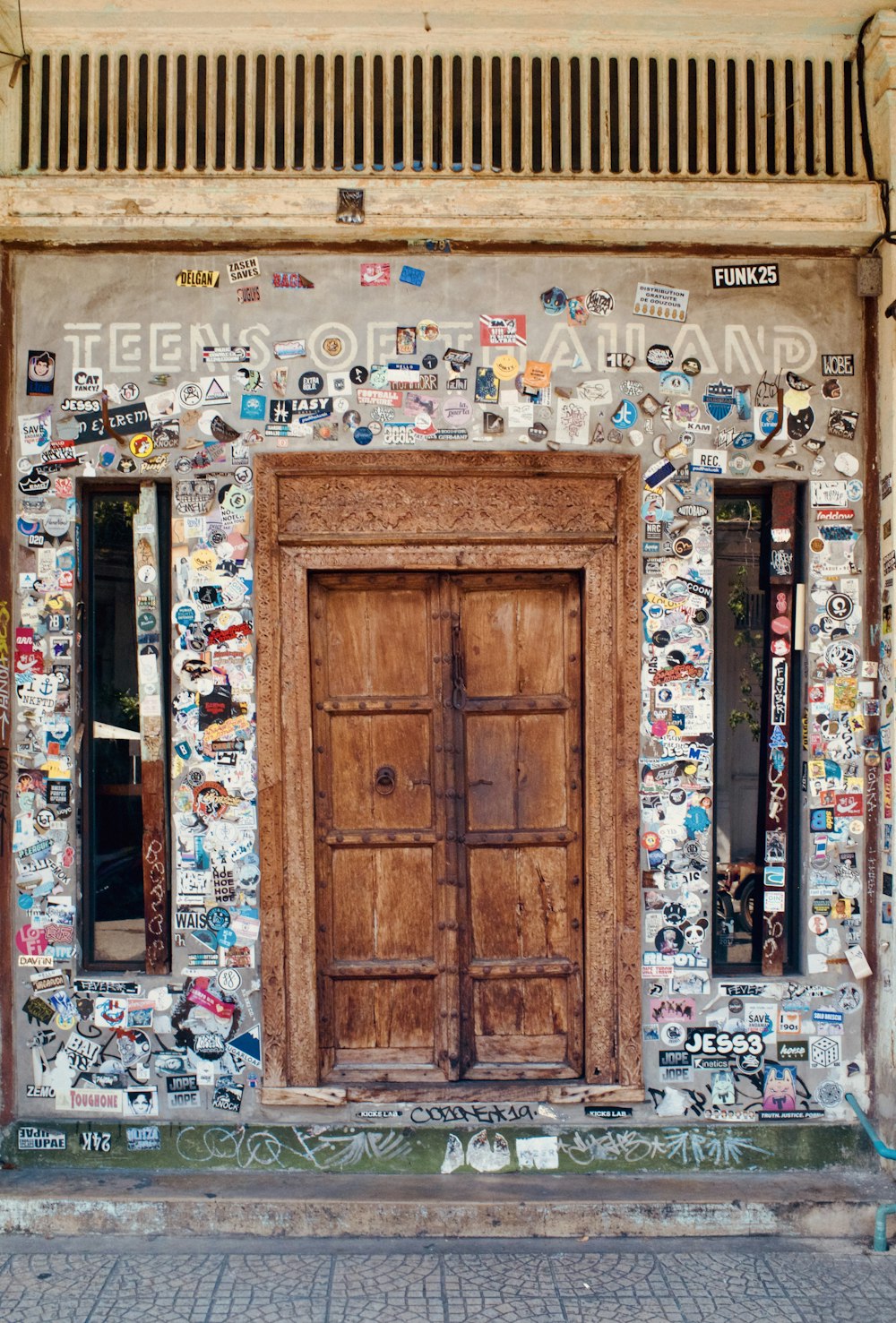 a wooden door sitting in front of a building covered in stickers