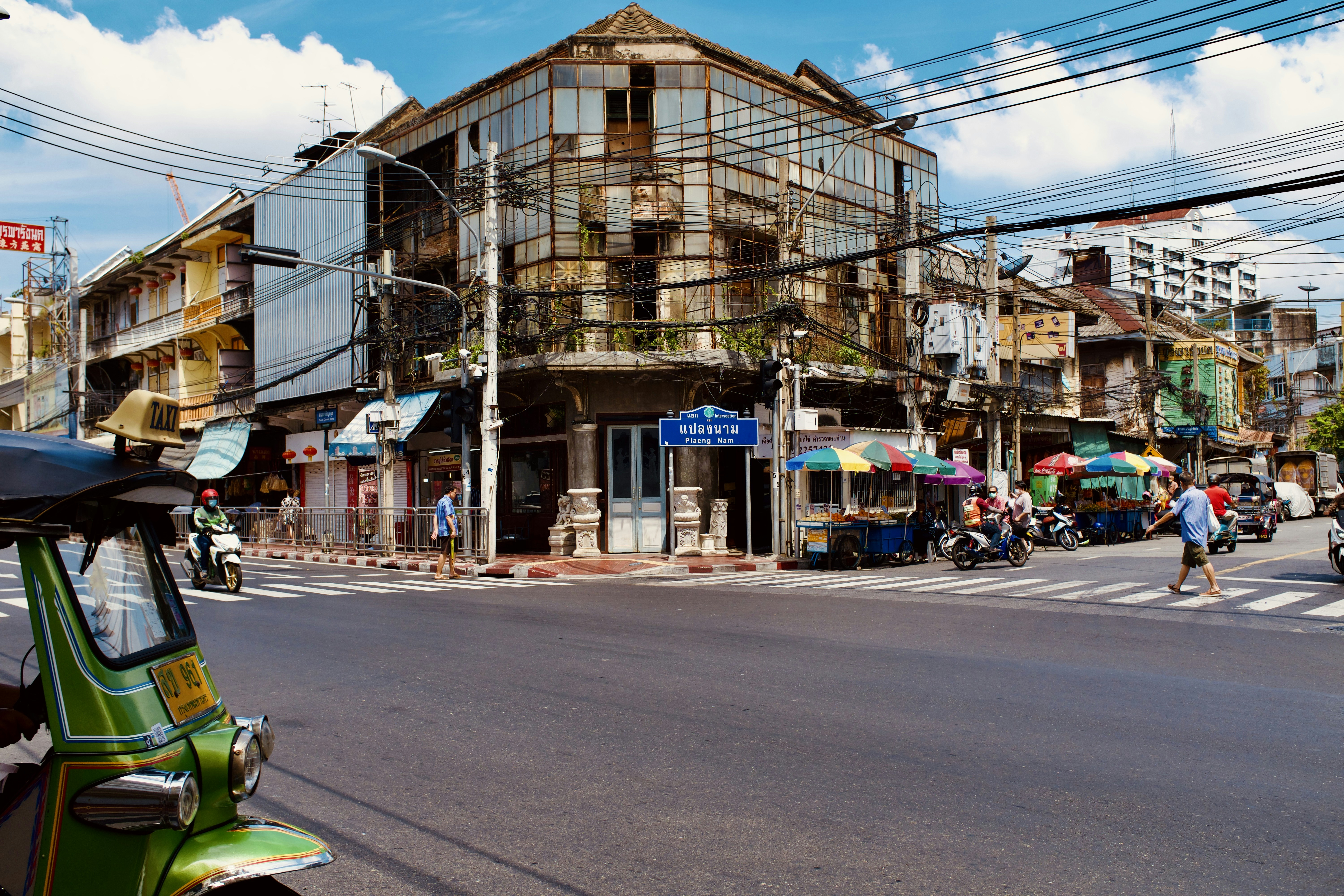 a small green car driving down a street next to tall buildings, 