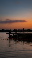A serene lakeside scene with an instructor guiding a small group of anglers casting their lines at sunset.