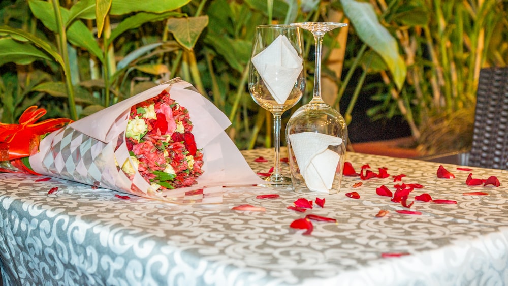 a table topped with a wine glass and a bouquet of flowers
