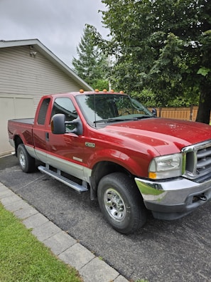 A fully replaced windshield on a pickup truck parked in a customer's driveway.