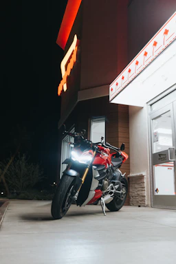A delivery motorcycle parked outside a modern Riyadh building at sunset.