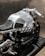 A sleek, silver motorcycle showcasing a modern, metallic design with visible components and a black cushioned seat. The motorcycle features intricate engineering details and a sturdy frame, emphasizing its mechanical aesthetic.