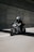 A motorcyclist wearing a helmet rides a sleek motorcycle with a unique black and white geometric pattern on its body. The rider is on a road within a tunnel, creating a dynamic and fast-paced scene.