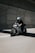 A motorcyclist wearing a helmet rides a sleek motorcycle with a unique black and white geometric pattern on its body. The rider is on a road within a tunnel, creating a dynamic and fast-paced scene.