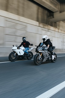 two people riding motorcycles on a city street