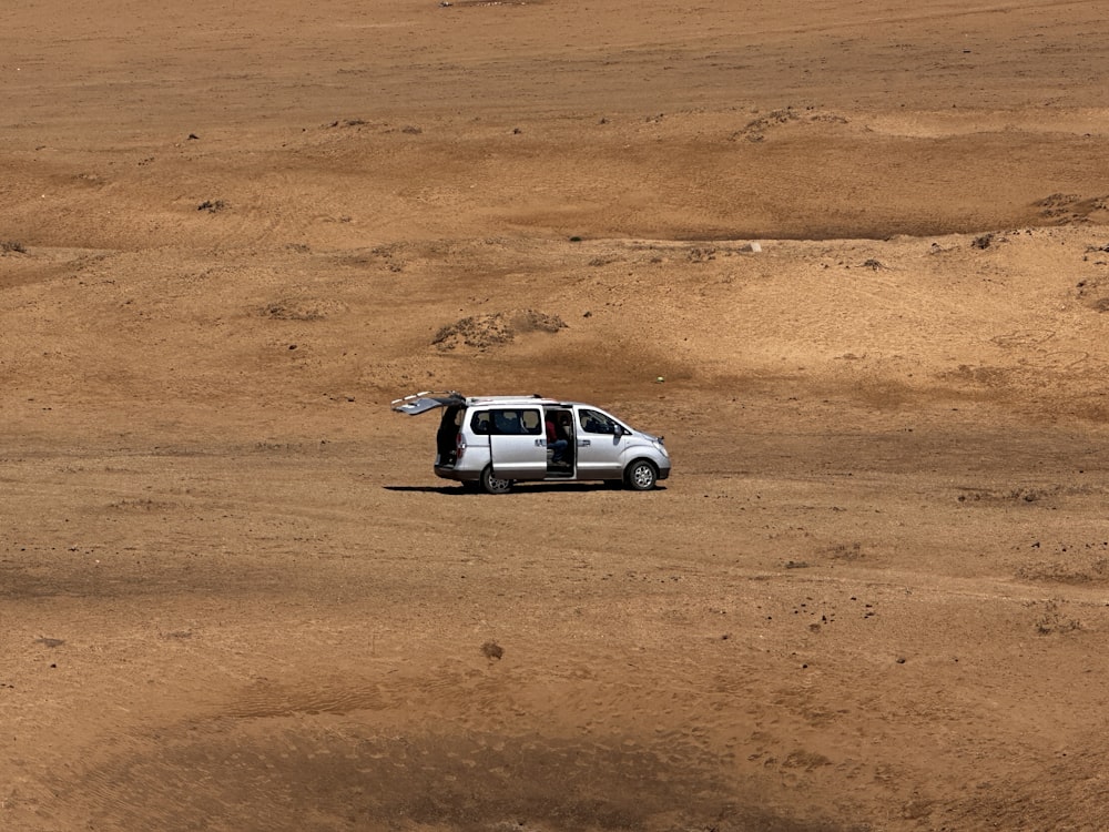 a small white van parked in the middle of a desert