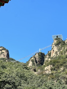 A sky glass bridge spanning between two mountain peaks with visitors walking.