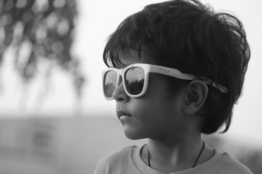 a young boy wearing sunglasses and a t - shirt