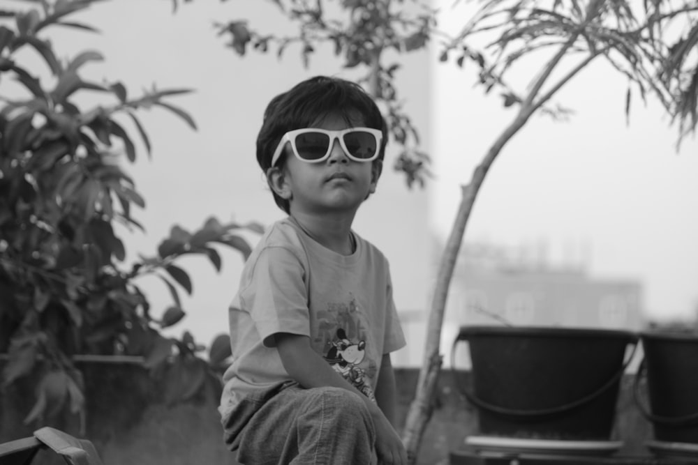 a young boy wearing sunglasses sitting on a bench
