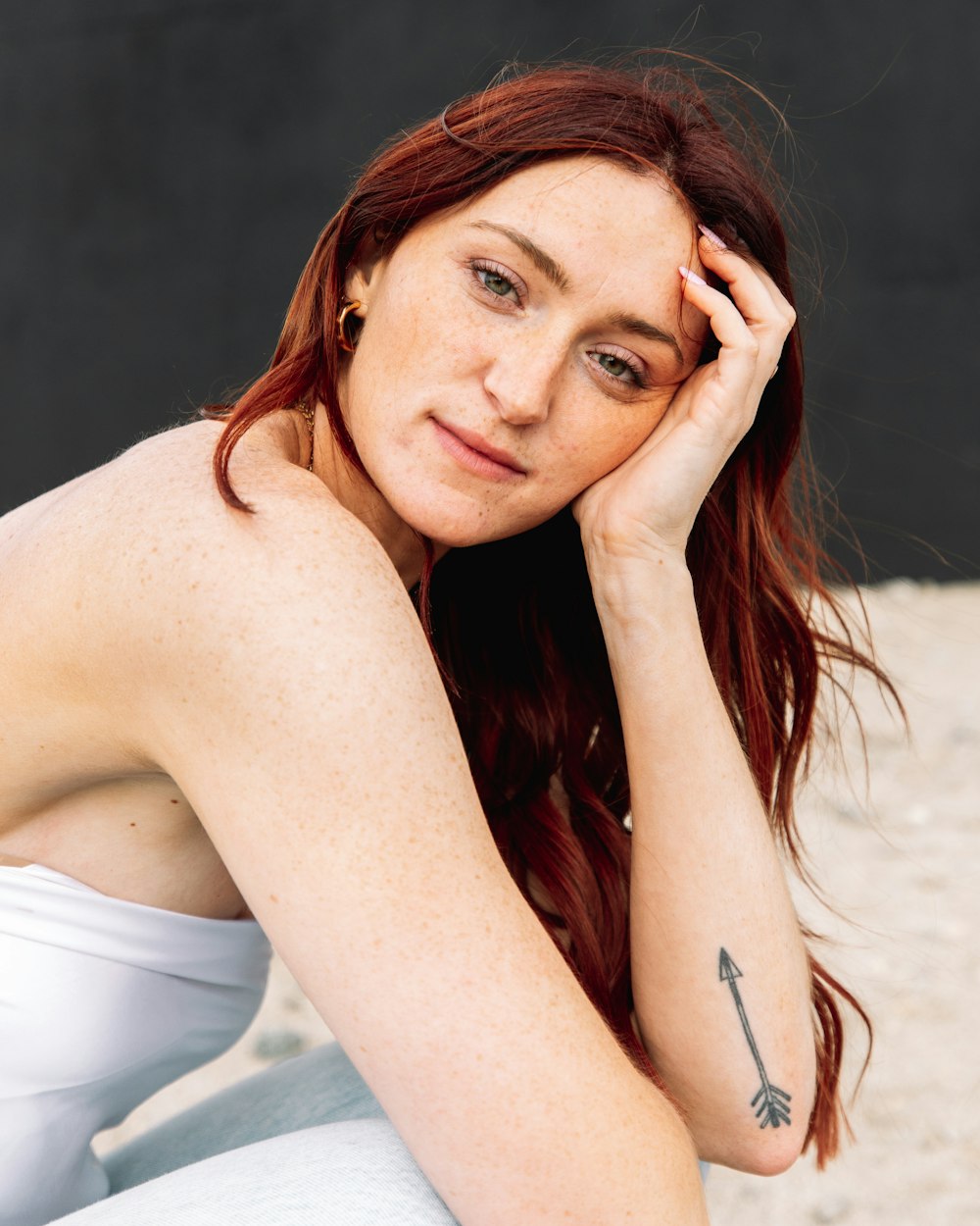 uma mulher com cabelos ruivos sentada na praia