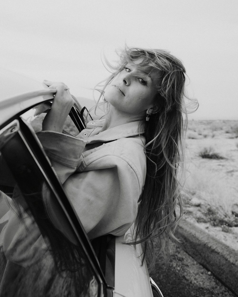 a woman with long hair leaning out of a car window