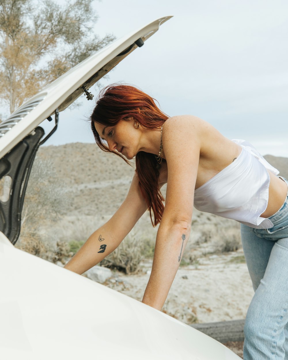 a woman leaning on the hood of a car