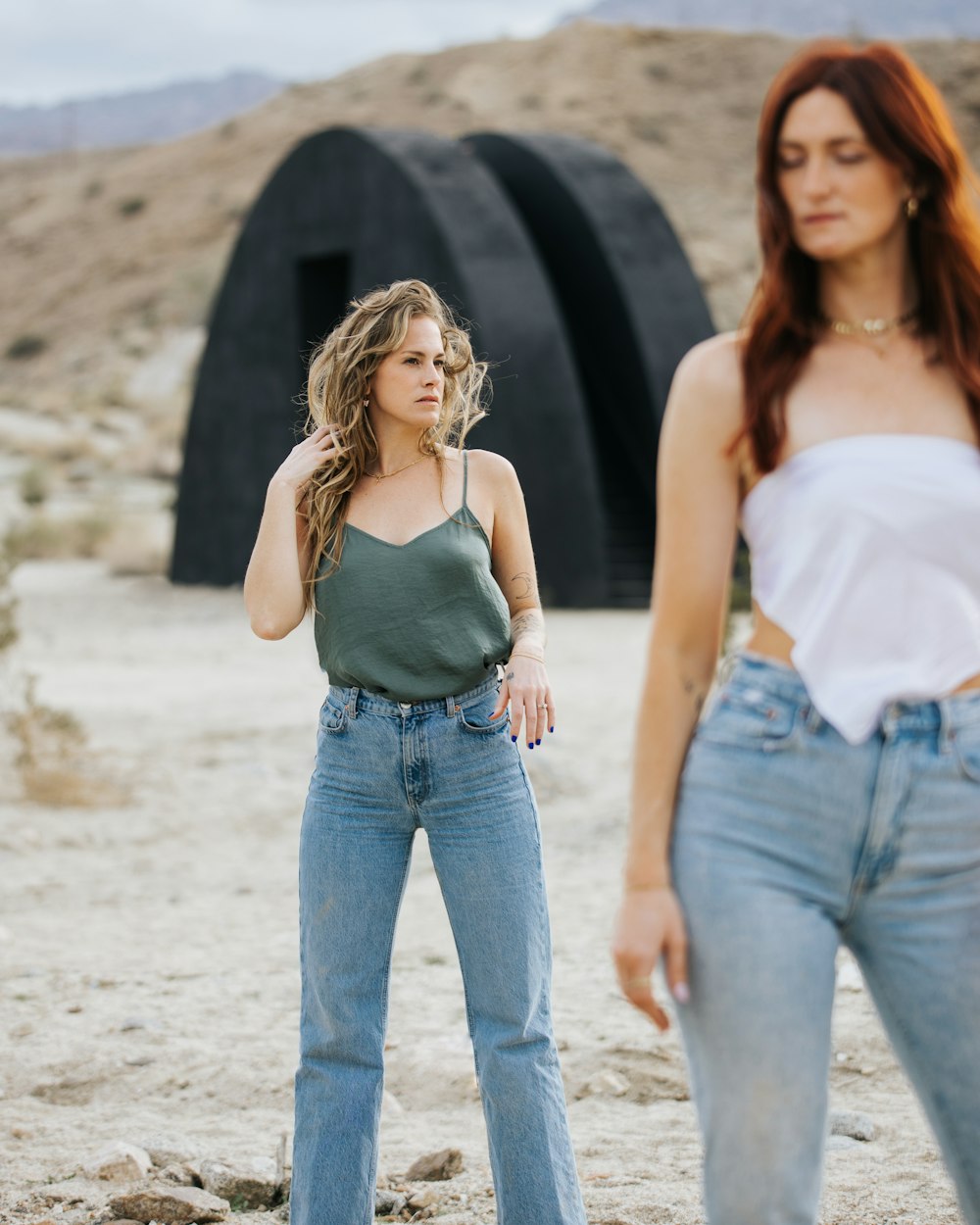 duas mulheres em pé no deserto com uma segurando a cabeça