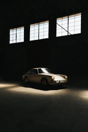 A classic vintage car in pristine condition parked in a sunlit garage.