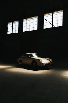 A classic vintage car in pristine condition parked in a sunlit garage.