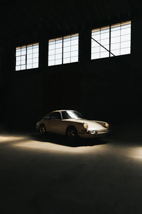 A sleek, glossy vintage car inside a stylish, dimly lit luxury garage with metallic gray and gold accents.