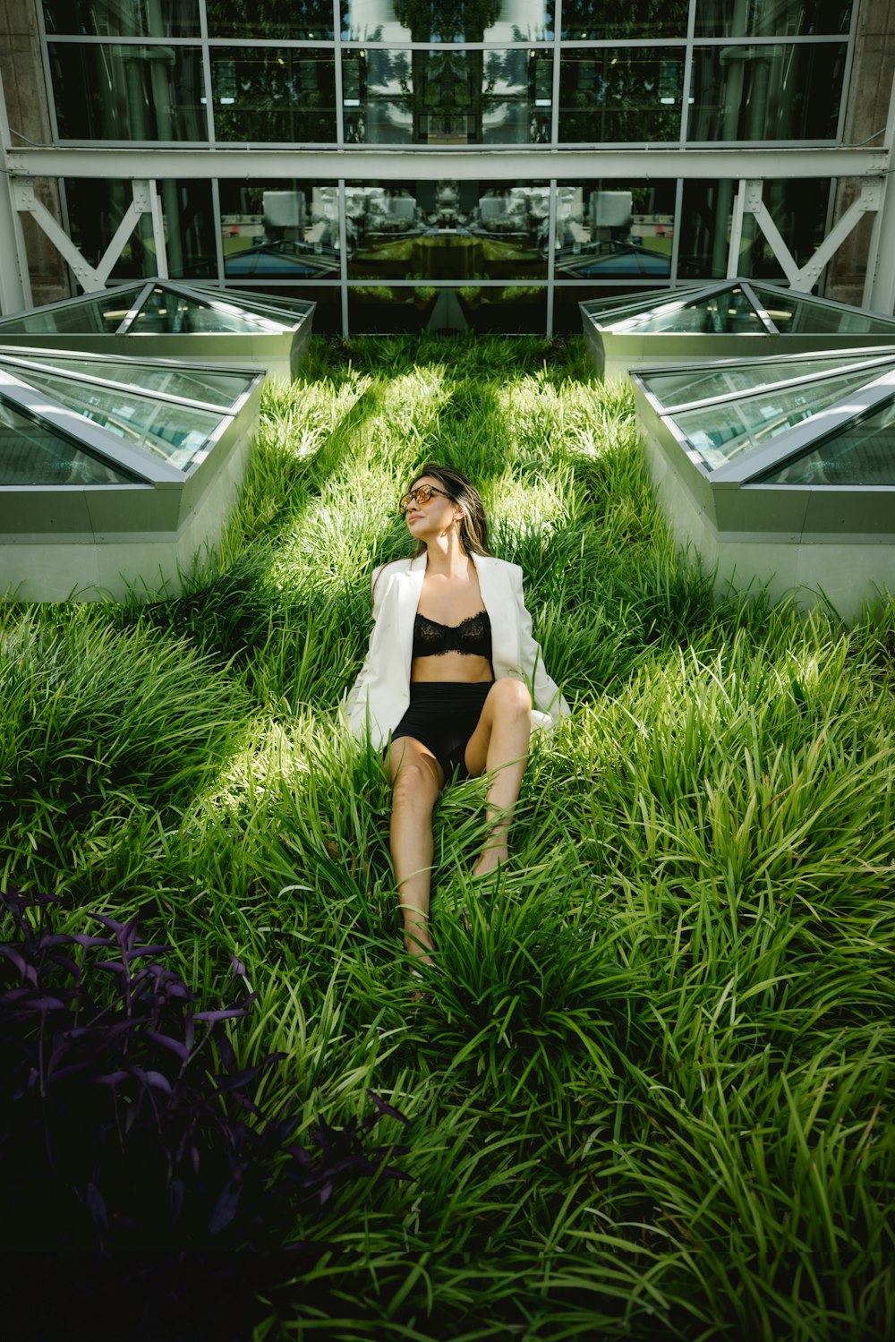 a woman sitting in the grass in front of a building