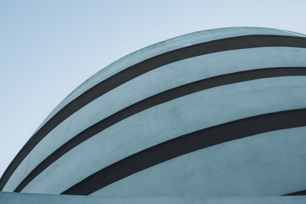 a tall building with a curved roof and a blue sky in the background