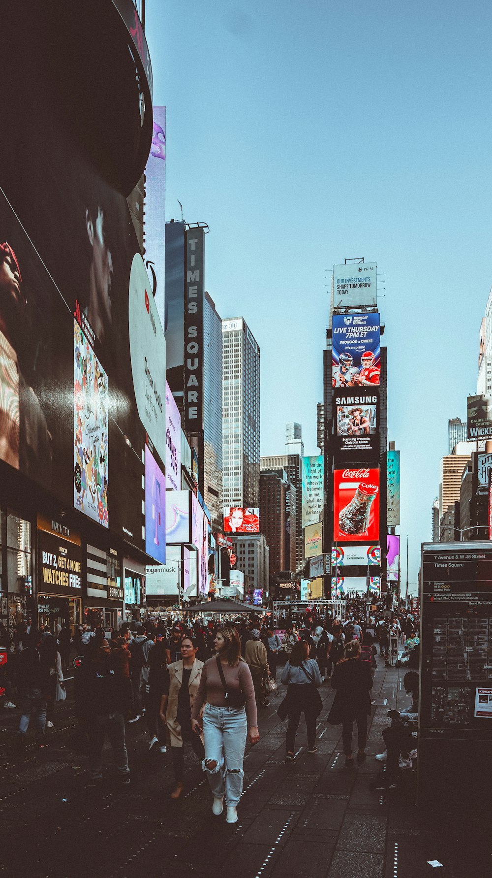 a crowd of people walking down a street next to tall buildings