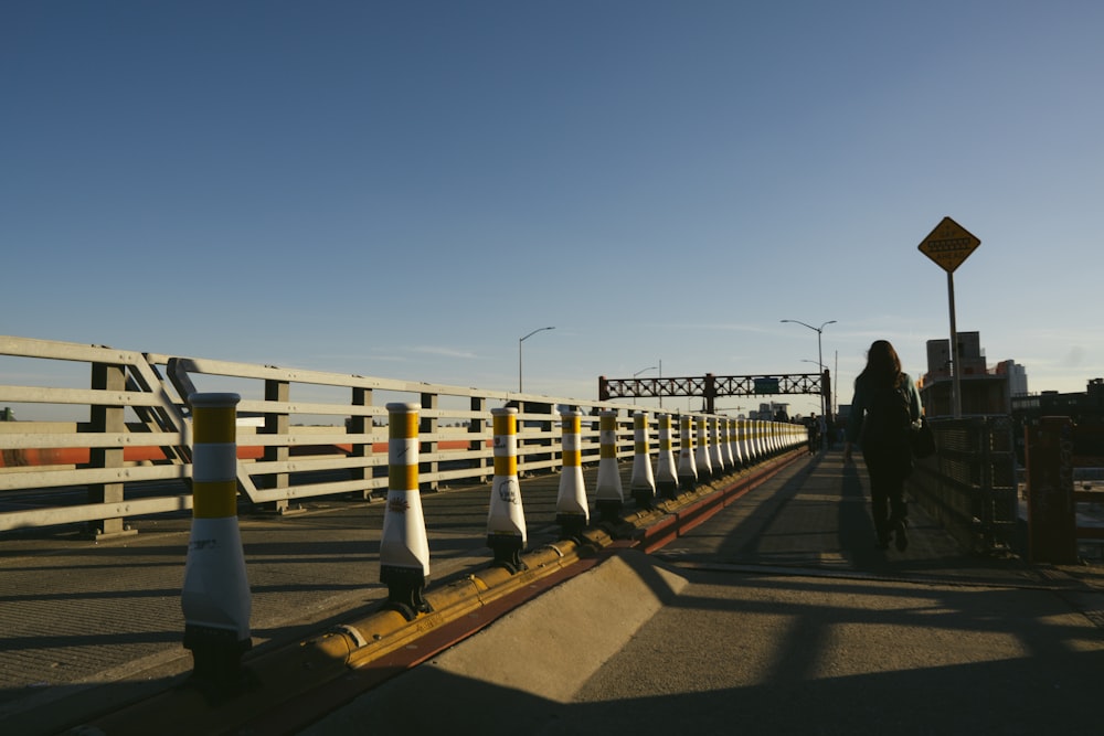 a woman walking across a bridge over a street