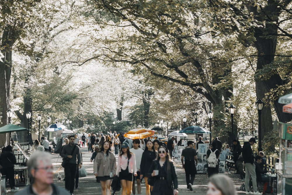 a crowd of people walking down a street next to trees