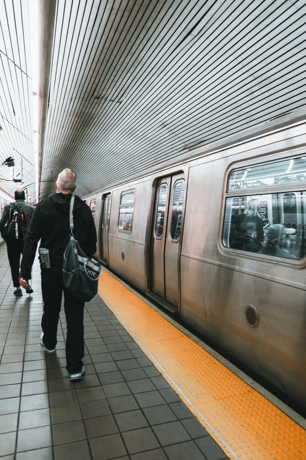 a group of people walking next to a silver train