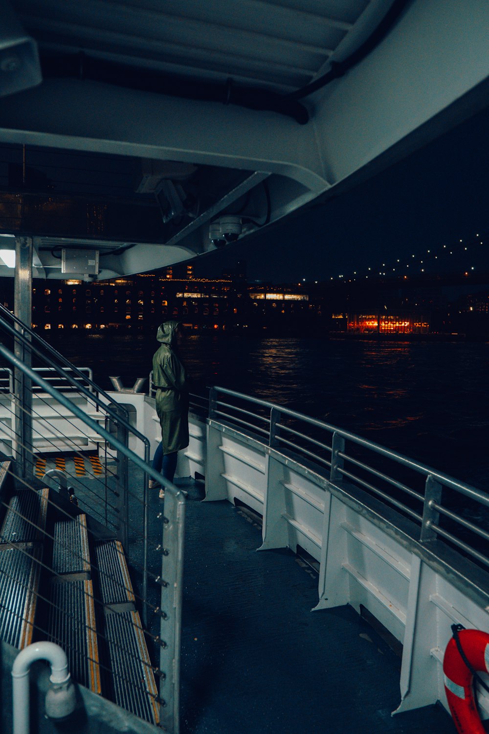 a man standing on the deck of a boat at night