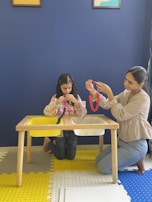 Two girls crafting colorful art projects at a table.