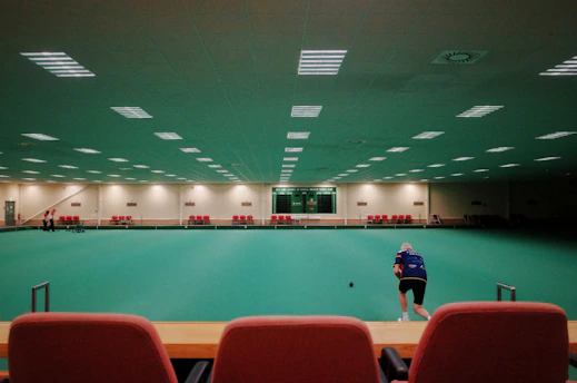 A vibrant indoor pickleball court with neon green lines and players warming up.