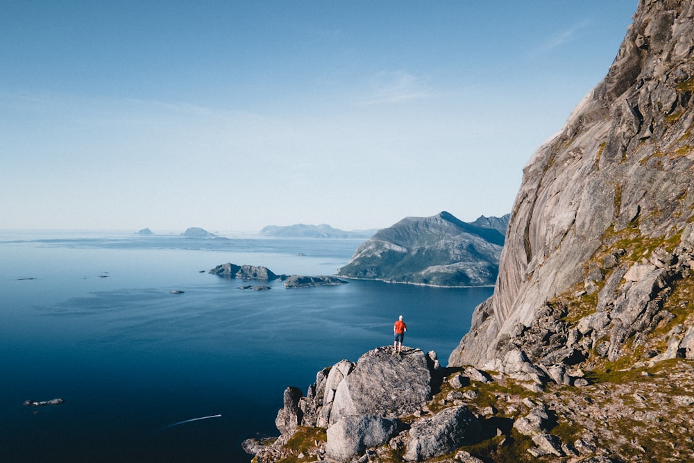 a person standing on top of a mountain next to a body of water